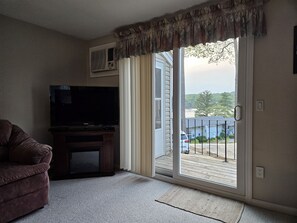 Relax in this cozy living space with a flat-screen TV and comfortable sofa, leading out to an outdoor area with a deck and neighborhood views.