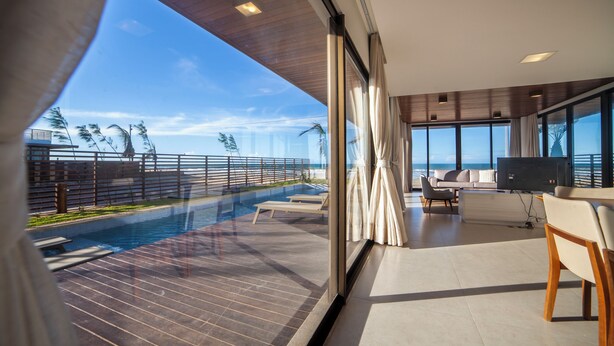 A modern living room with a large window overlooking a pool and ocean view. - ILLA BLUE VILLAGE (Trairi)