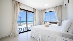 A modern hotel room with a large bed, a view of the beach, and a balcony with a railing. - ILLA BLUE VILLAGE (Trairi)