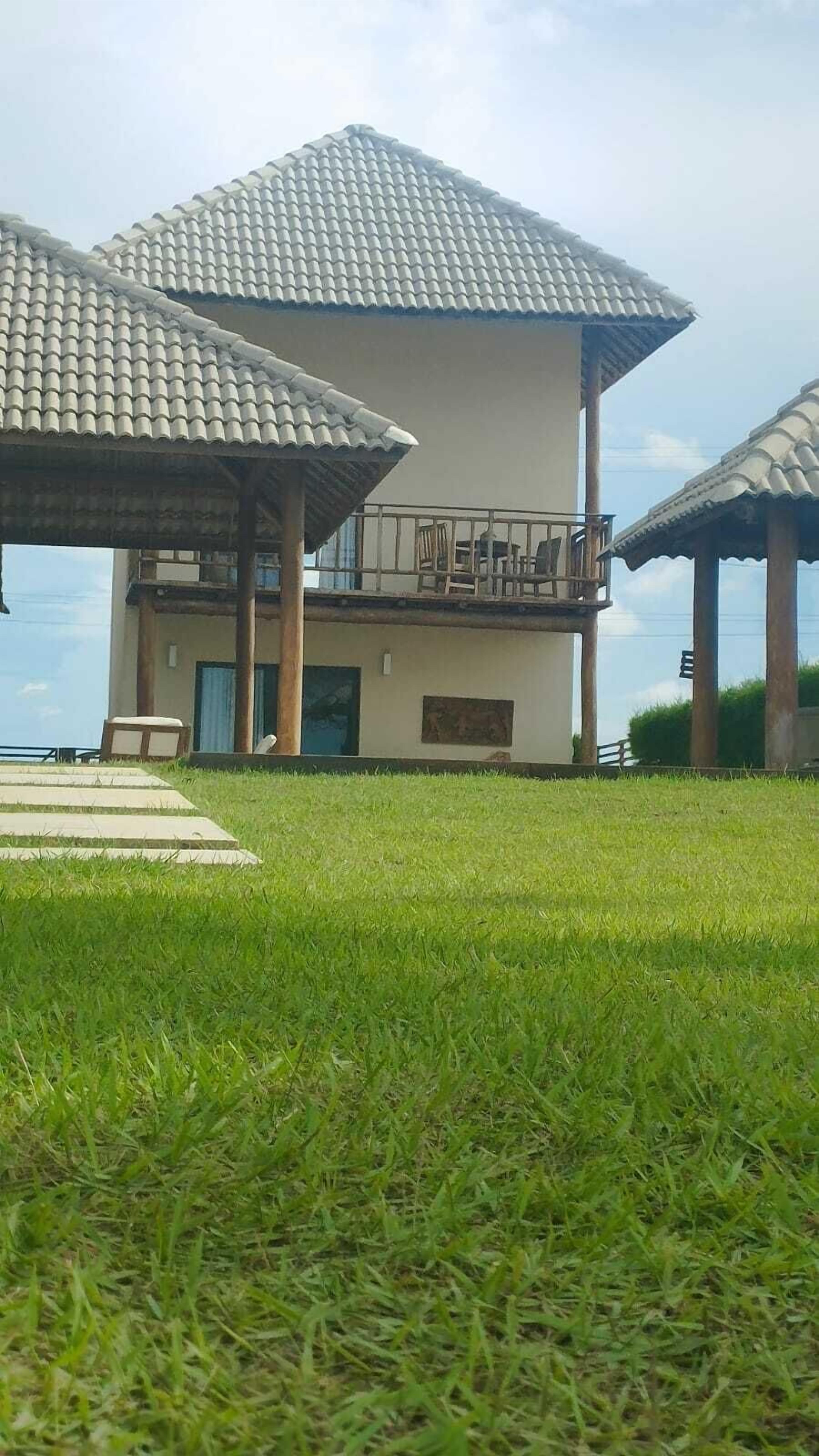 A building with a tiled roof and a balcony. There is a grassy area in the foreground.