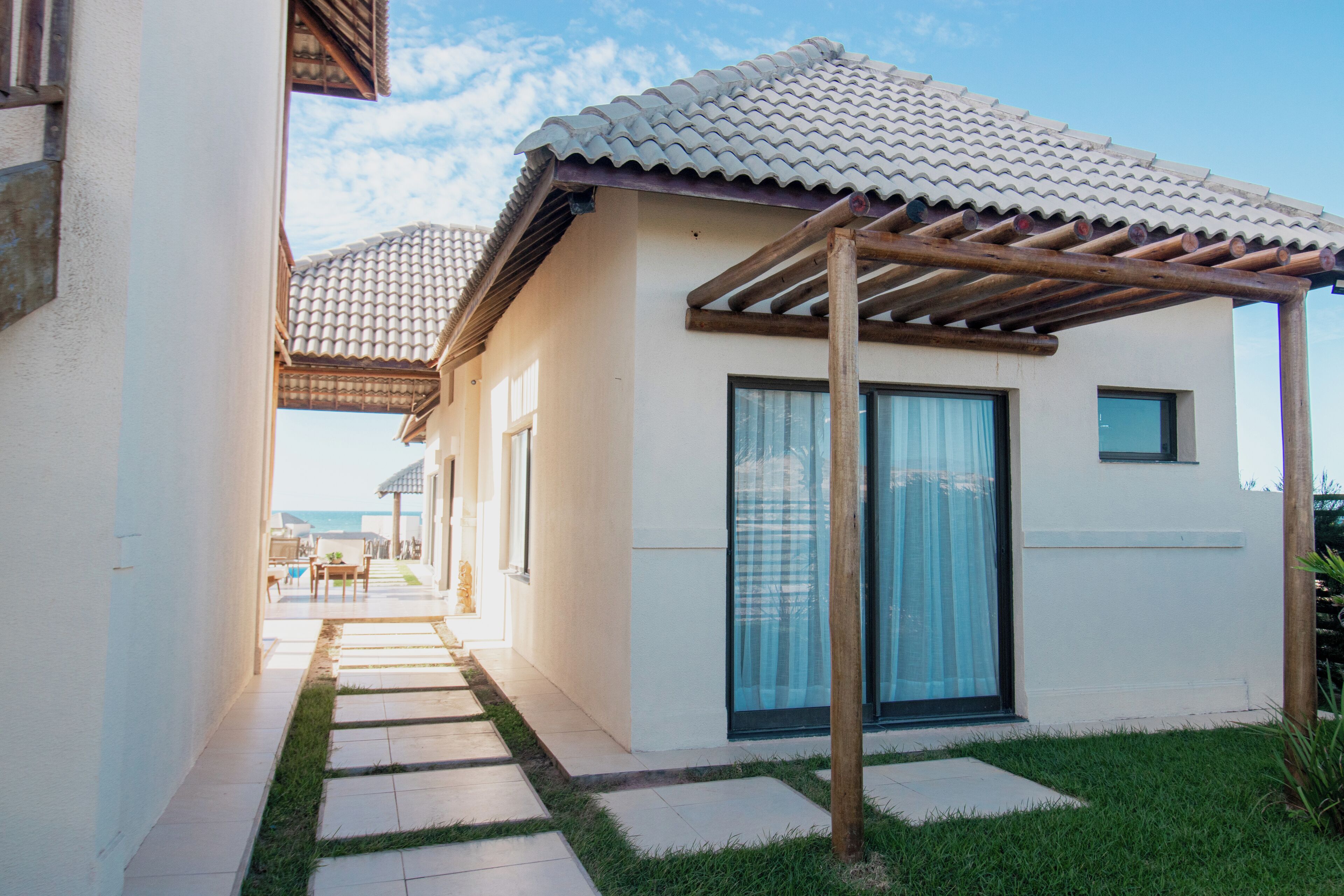 A modern house with a tiled roof, a covered patio, and a pathway leading to the entrance.