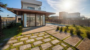 A modern house with a glass facade, a stone pathway, and a well-maintained lawn. - ILLA BLUE VILLAGE (Trairi)