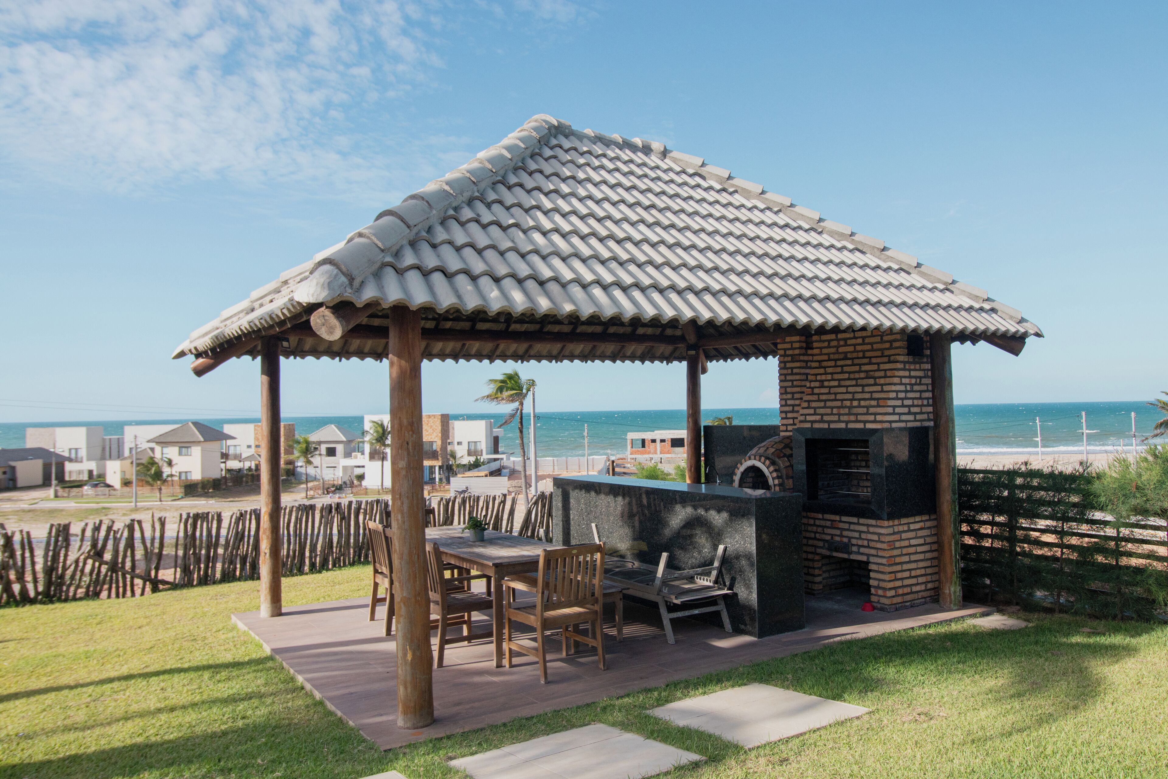 Een prieeltje met pannendak met uitzicht op een strand, een barbecueplaats met bakstenen en een uitzicht op de oceaan.