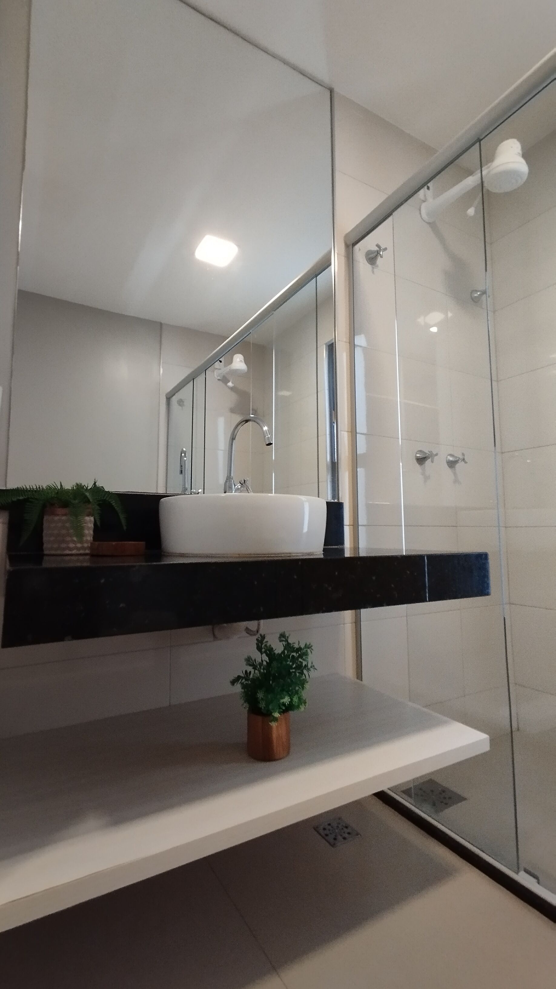 A modern bathroom with a white sink, a mirror, and a glass shower enclosure.