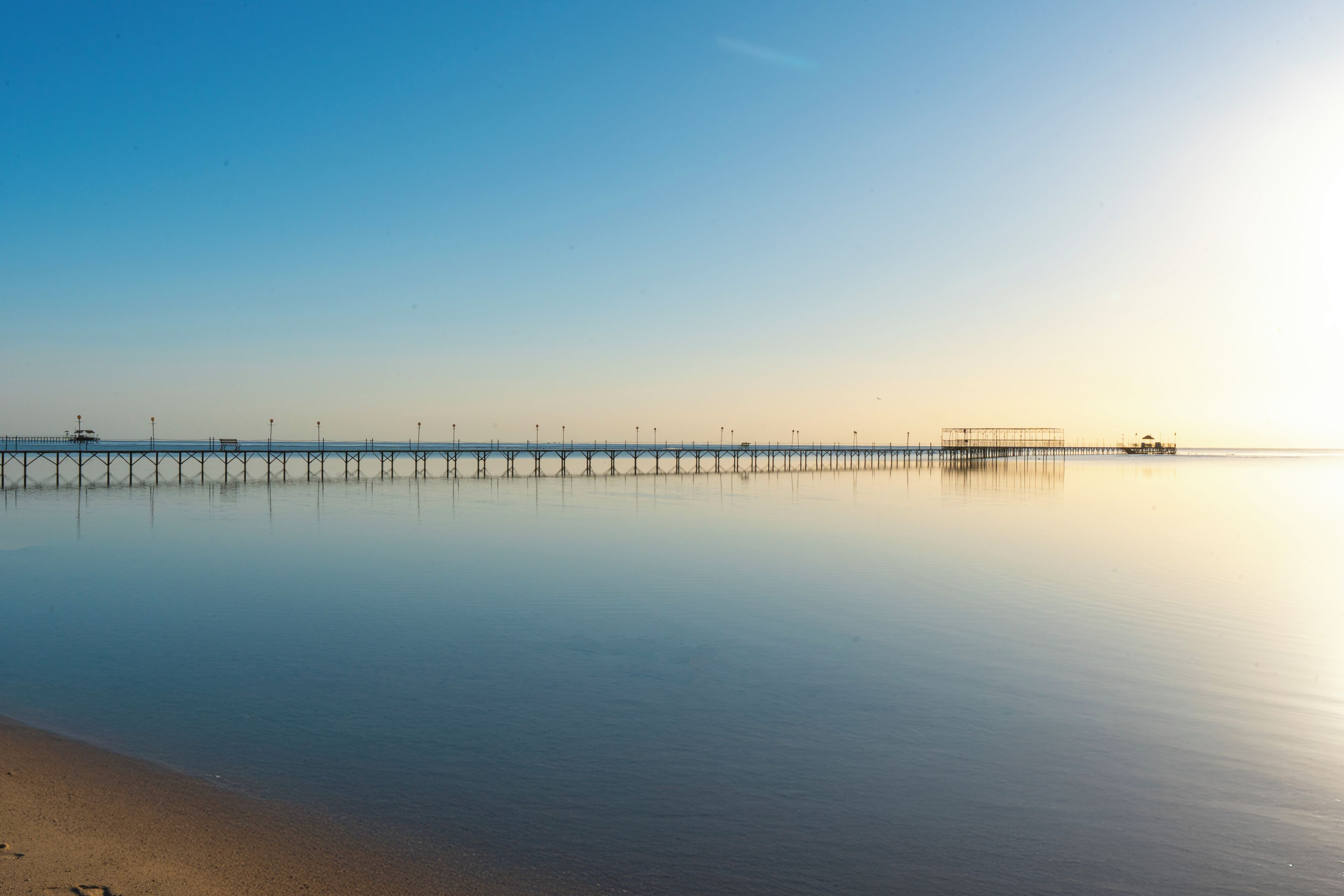 A calm beach with a pier extending into the water.