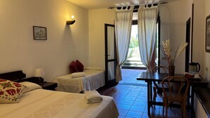 Une chambre d’hôtel avec deux lits, une table à manger, des chaises, une machine à café et une vue sur l’extérieur.