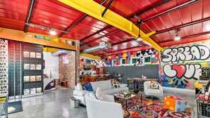 A vibrant interior with a red ceiling, a white sofa, colorful artwork, and a 'Spread Love' mural. - The ArtHouse: Where Industrial Charm Meets Creative Inspiration (St. Augustine)