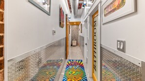 A hallway with a colorful rug, a 'One Way' sign, and a 'Bathroom' sign on the walls. - The ArtHouse: Where Industrial Charm Meets Creative Inspiration (St. Augustine)
