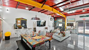 A spacious room with a large table, a sofa, and a bike. - The ArtHouse: Where Industrial Charm Meets Creative Inspiration (St. Augustine)