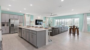 Una cocina moderna con gabinetes grises, un refrigerador de acero inoxidable y una isla grande.