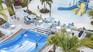 Un parque acuático con piscina de olas, toboganes y zona de juegos.