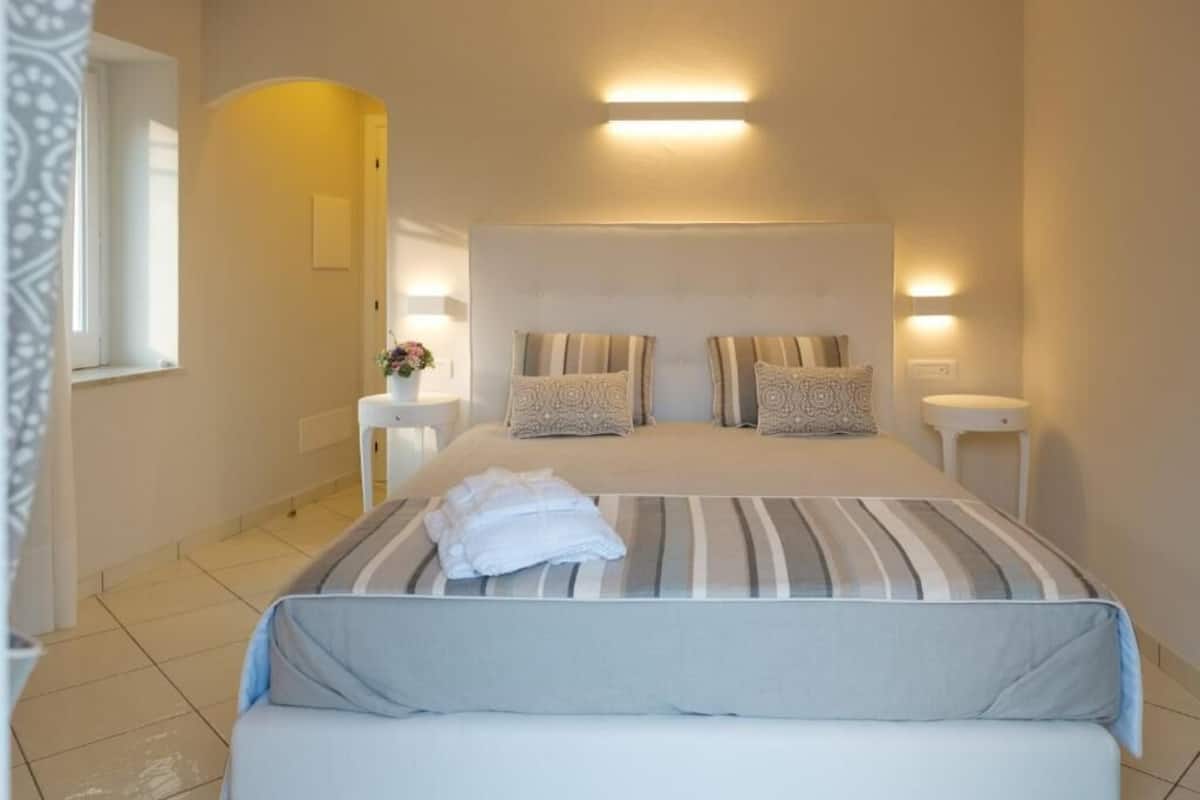 A neatly arranged bedroom with a large bed, two bedside tables, and a small bedside lamp.