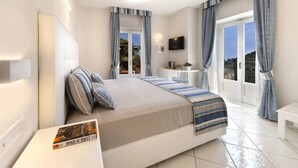 A bedroom with a bed, bedside tables, a TV, and a view of the outdoors. - Villa Carlotta Minori (Minori)