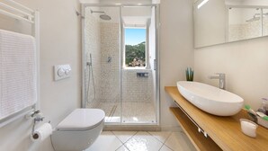A modern bathroom with a glass-enclosed shower, a white toilet, and a wooden vanity with a large sink. - Villa Carlotta Minori (Minori)