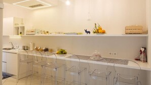 A modern kitchen with white cabinetry, a white countertop, and clear plastic bar stools. - Villa Carlotta Minori (Minori)