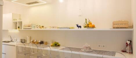 Una cocina moderna con armarios blancos, encimera blanca y taburetes de barra de plástico transparente.