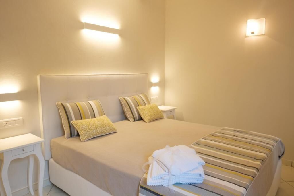 A neatly made bed with striped bedding, two pillows, and a folded towel on the side.