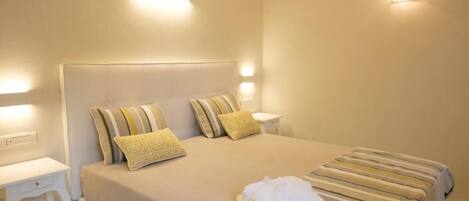 A neatly made bed with striped bedding, two pillows, and a folded towel on the side.