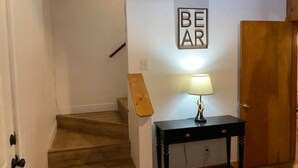 En trappa som leder upp till en liten plattform med ett träräcke, en väggmonterad skylt med texten ”BJÖRN” och ett litet bord med en lampa.