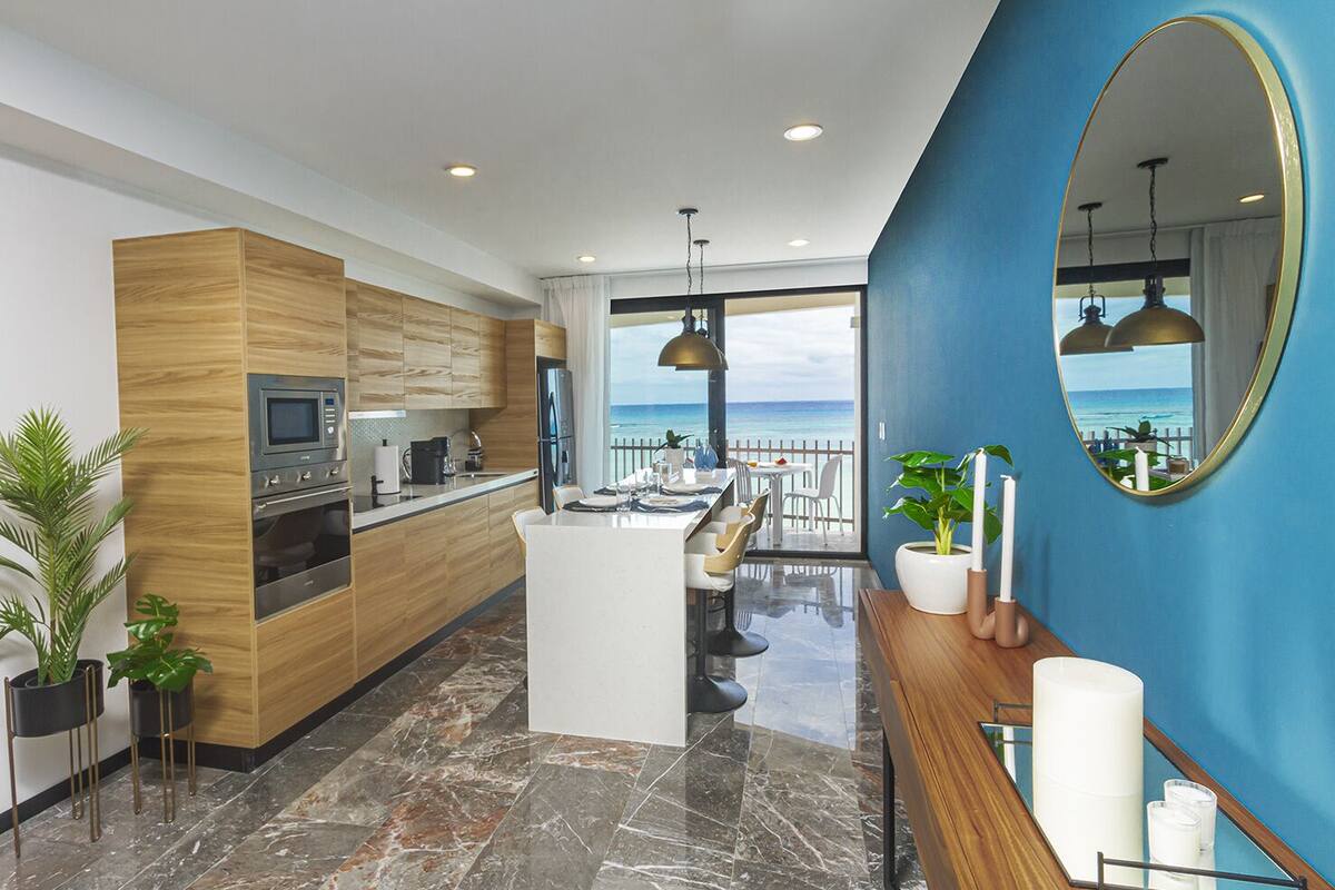 A modern kitchen with a central island, wooden cabinetry, and a view of the ocean.