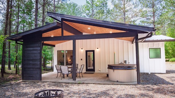Une cabane dotée d’un patio couvert, d’un jacuzzi et d’un foyer extérieur.
