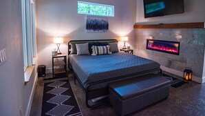 Une chambre à coucher moderne avec un lit, des lampes de chevet, une cheminée et un téléviseur.