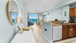 Una cocina moderna con una isla central, un área de comedor con sillas y vista al océano.
