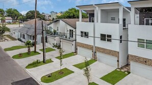A modern residential area with two-story houses, a well-maintained lawn, and a clear sky.