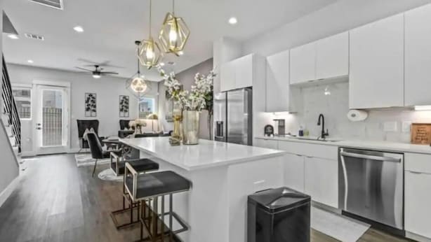 A modern kitchen with white cabinets, stainless steel appliances, and a central island with bar stools.