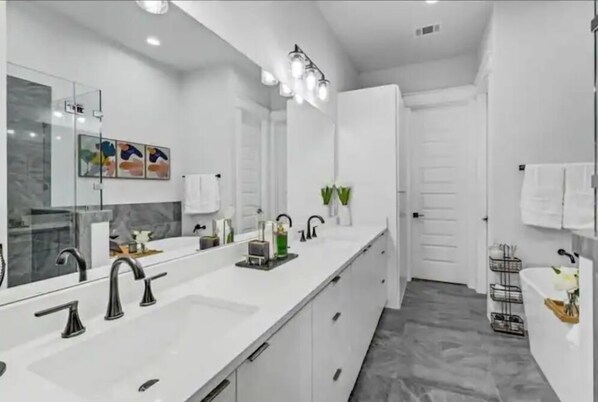 Un baño moderno con un espejo grande, dos lavamanos y una zona de ducha.