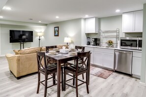 Cozy living space with a dining area and kitchen, featuring a sofa, flat-screen TV, and dining table with four chairs.