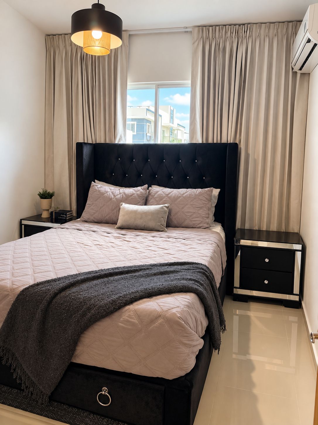 A modern bedroom with a large bed, a bedside table, a lamp, and a window with curtains.