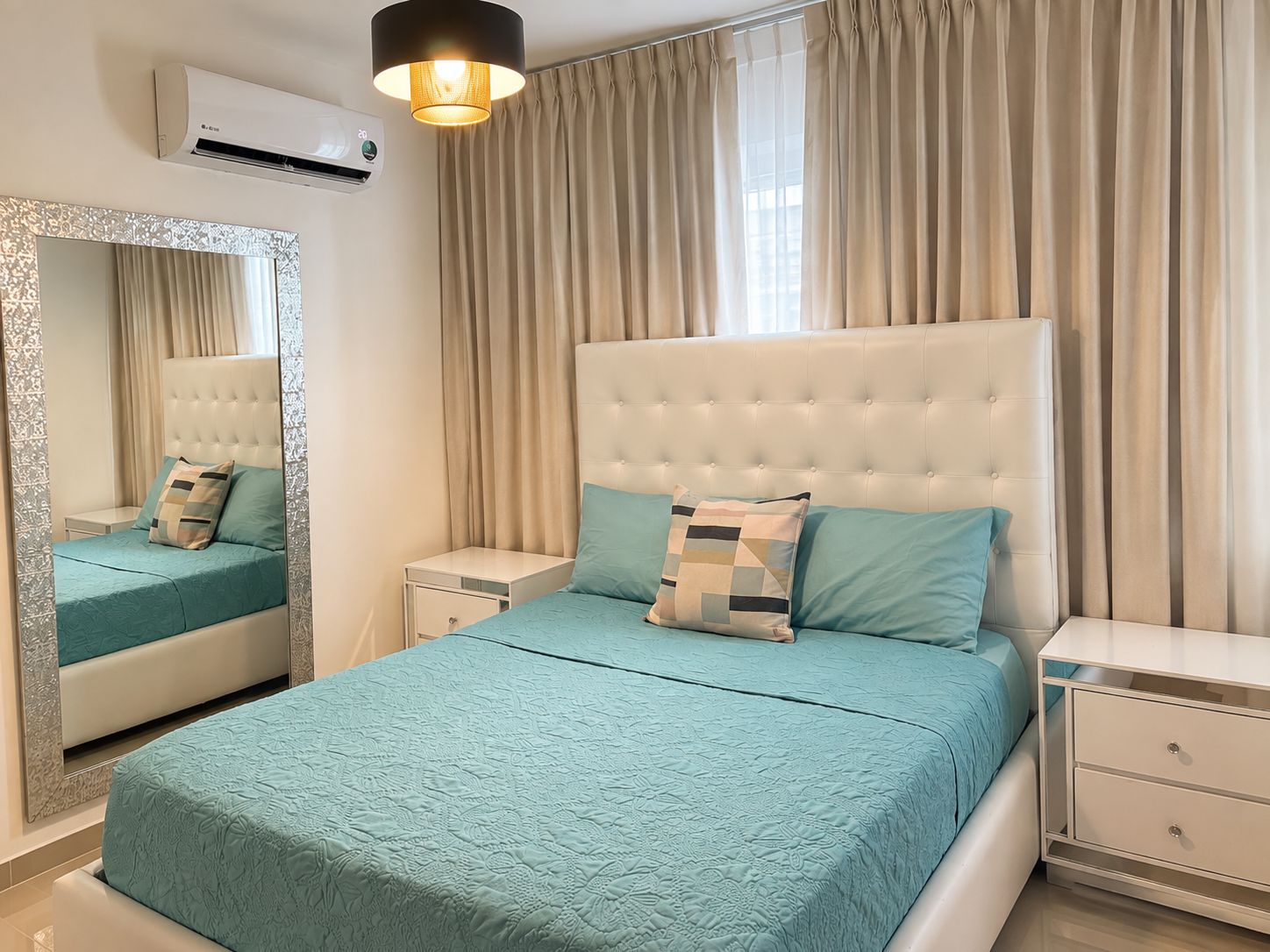 Un dormitorio con una cama grande, una mesita de noche, un tocador, un espejo y una lámpara en el techo.