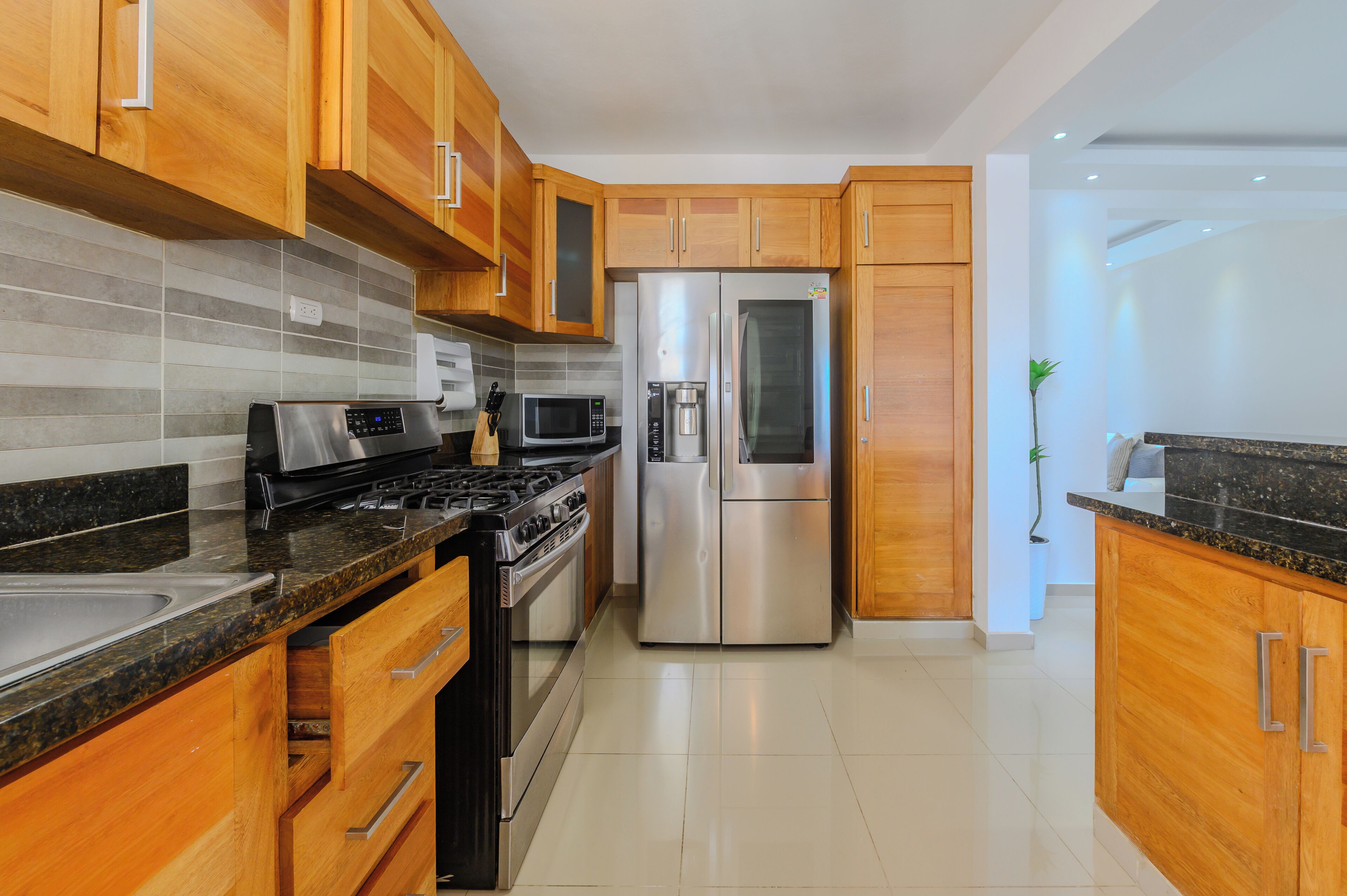 Una cocina moderna con armarios de madera, electrodomésticos de acero inoxidable y un salpicadero de azulejos.