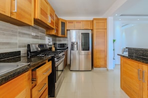 A modern kitchen with wooden cabinets, stainless steel appliances, and a tiled backsplash.
