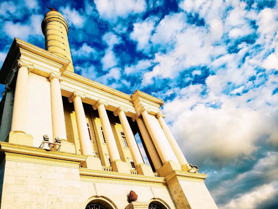 Ein Gebäude mit klassischer Architektur, mit Säulen und einem markanten Schornstein.