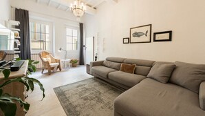 Un salon comprenant un canapé, un fauteuil, un bureau et un lustre.