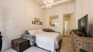 Une chambre à coucher avec un lit, une commode, une télévision et un miroir.