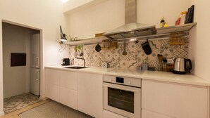 Une cuisine moderne avec des armoires blanches, un four en acier inoxydable, un micro-ondes encastré et un revêtement mural décoratif.