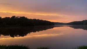A calm lake at sunset with a forested shoreline.