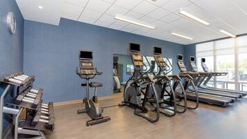 A gym with treadmills, elliptical machines, and a weight bench.