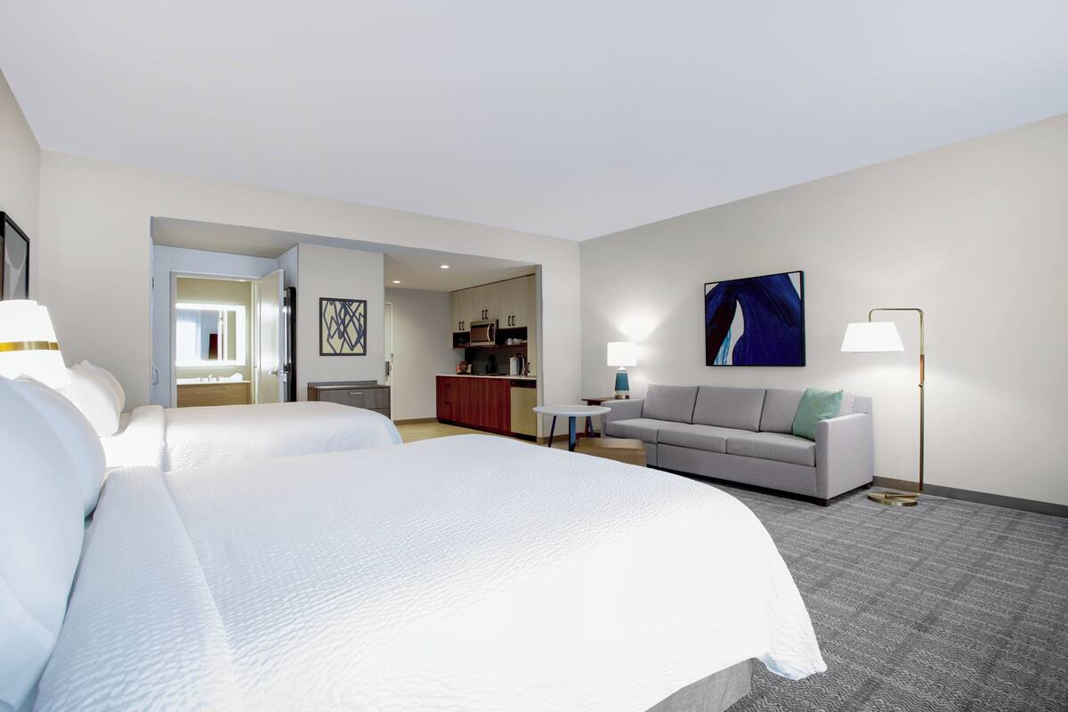 Una habitación de hotel con una cama grande, un sofá, un escritorio y una kitchenette.