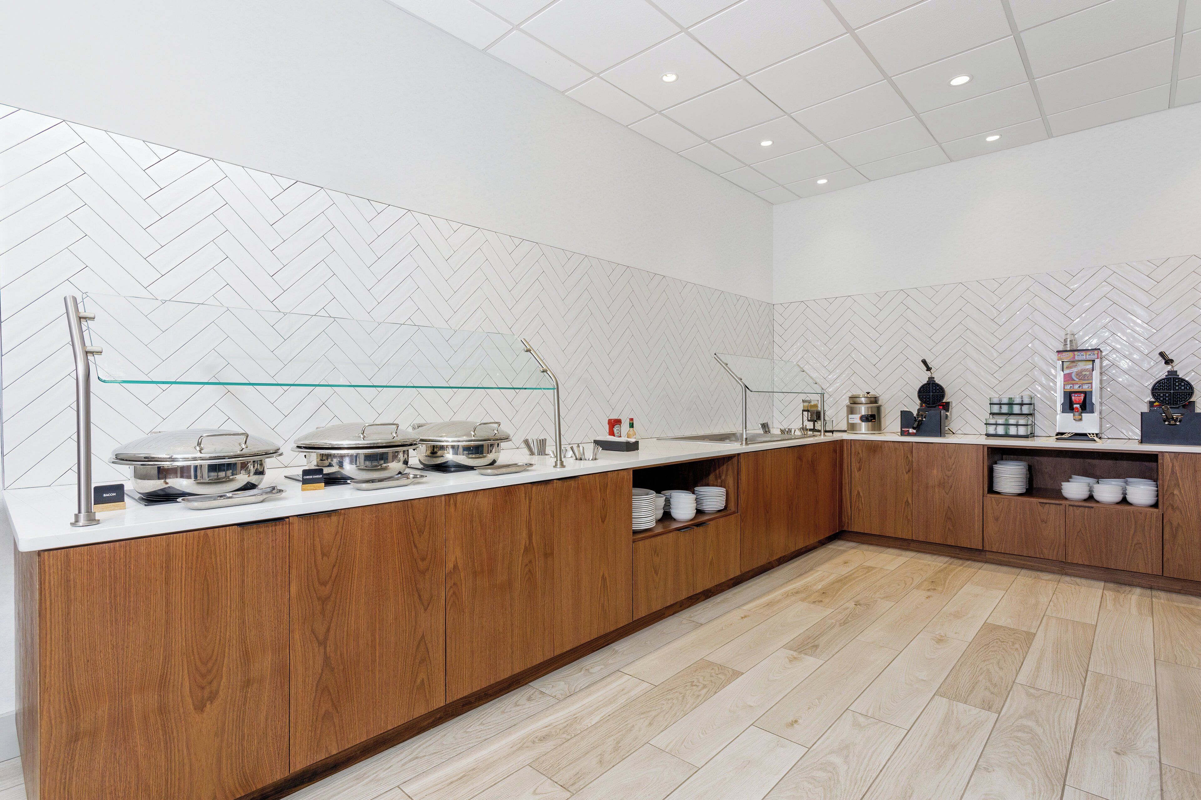 Una cocina moderna con armarios de madera, una encimera blanca y un salpicadero con motivo de espiga.