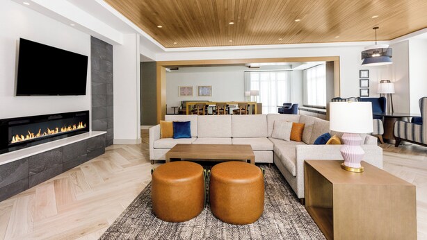 A modern living room with a fireplace, a sofa, a coffee table, and a TV mounted on the wall. - Staybridge Suites Winter Haven Auburndale by IHG (Winter Haven)