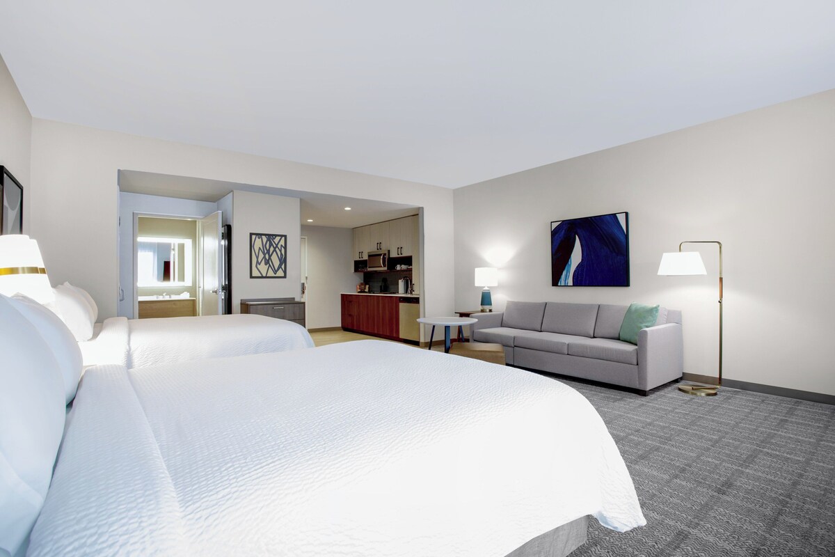 Ein Hotelzimmer mit einem großen Bett, einer Couch, einem Schreibtisch und einer Küchenzeile.