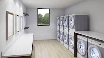 A laundry room with multiple washing machines, a window with a view of trees, and a light-colored floor.