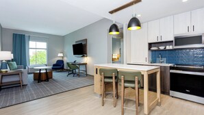 A modern kitchen with a dining area, a flat-screen TV, and a large window. - Staybridge Suites Winter Haven Auburndale by IHG (Winter Haven)