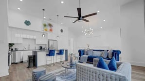 A modern living room with a blue sofa, a round coffee table, and a ceiling fan. - Stylish Cozy home near DT Houston and Medical Cntr (Houston)