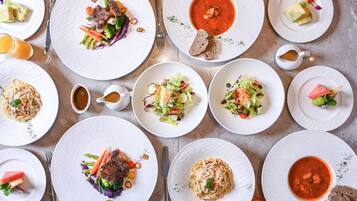 A table set with various dishes including pasta, salads, and soup, arranged neatly on white plates.