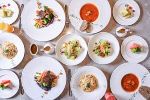 Una mesa con varios platos, incluyendo pasta, ensaladas y sopa, dispuestos ordenadamente sobre platos blancos.